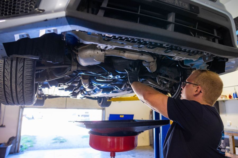 A man is working under a car in a garage.