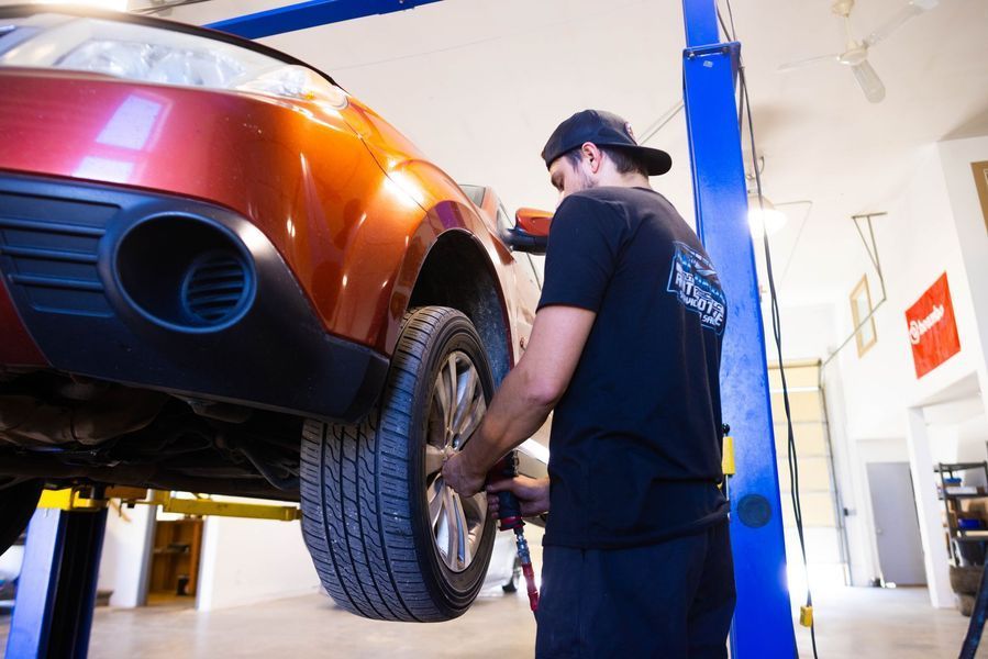 A man is working on a car on a lift in a garage.