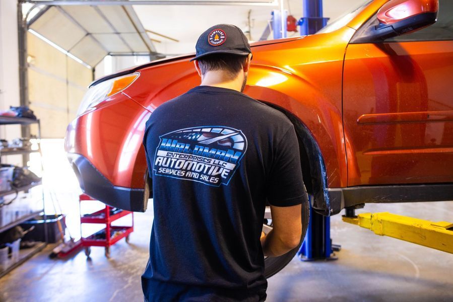 A man is working on a car on a lift in a garage.