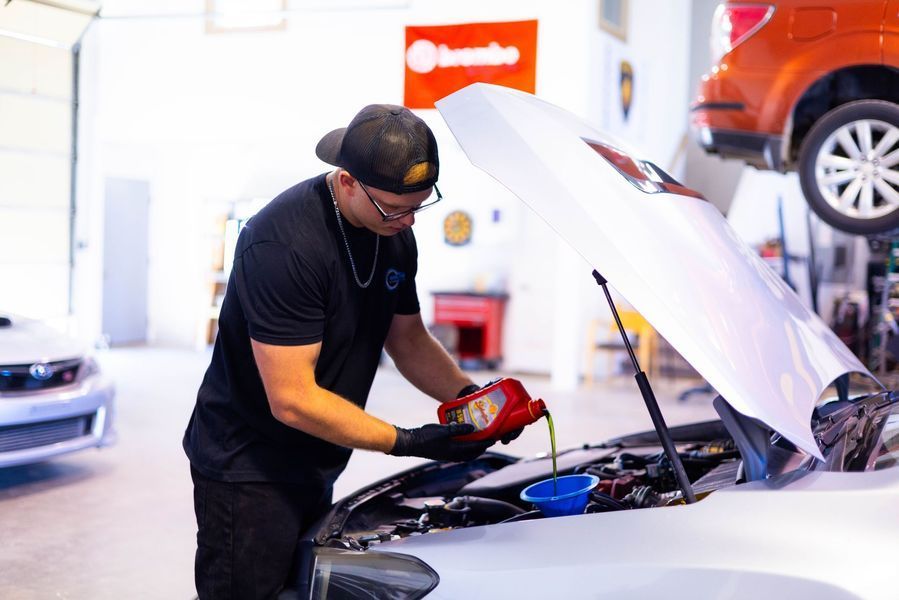 A man is pouring oil into the engine of a car.