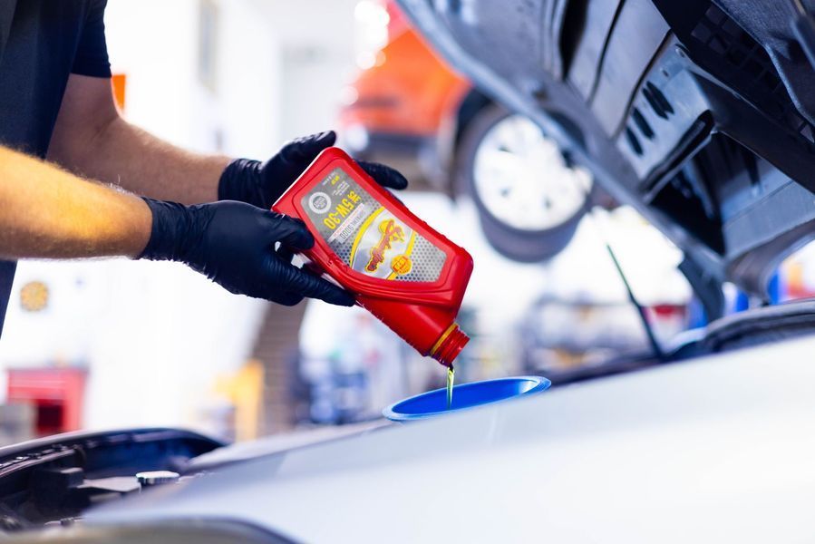 A man is pouring oil into the engine of a car.