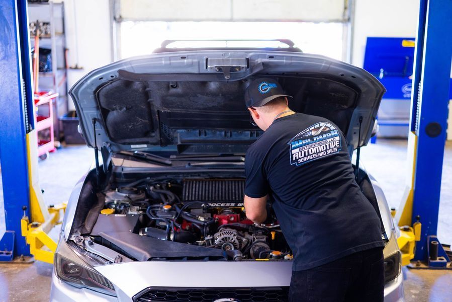 A man is working on the engine of a car in a garage.