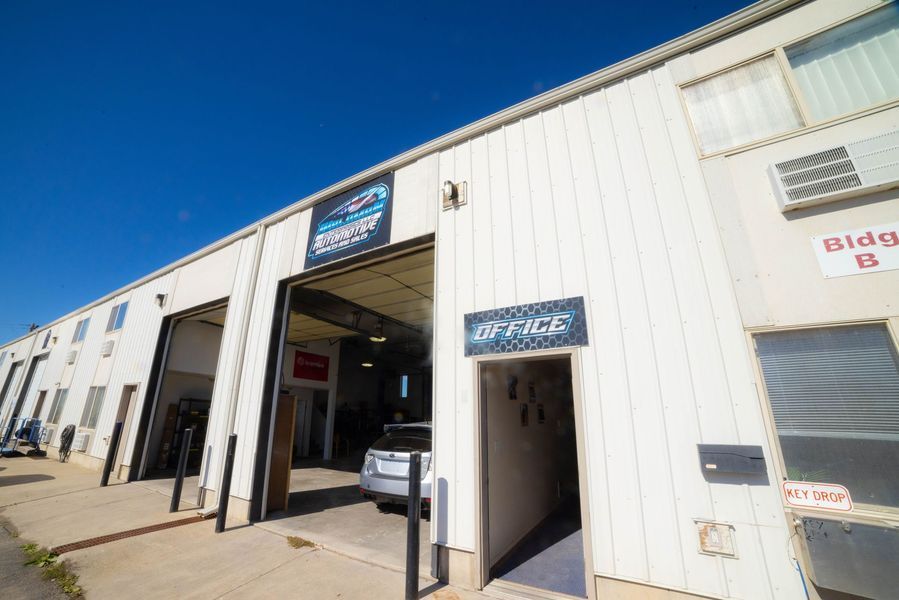 A white building with a car parked in front of it.