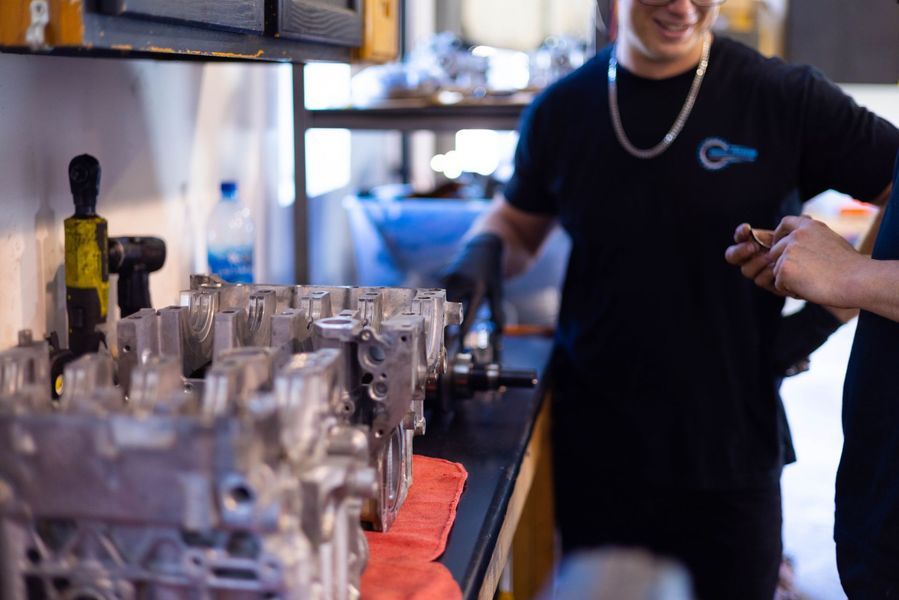 Two men are working on a car engine in a garage.
