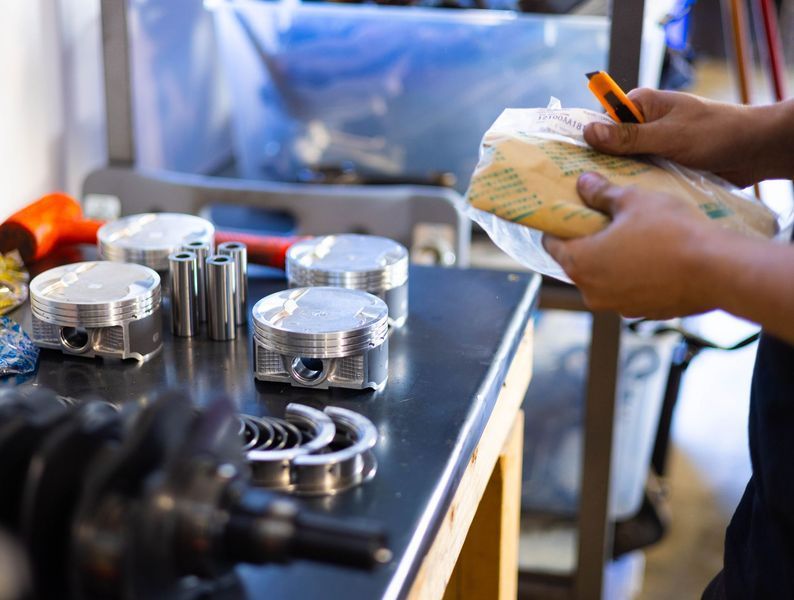 A person is holding a piece of paper in front of a table with pistons on it.