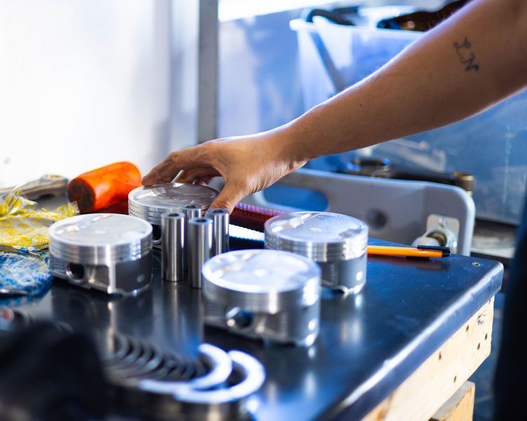 A person is reaching for a piston on a table.