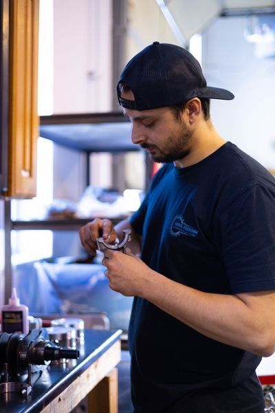 A man in a baseball cap is working on a machine in a kitchen.