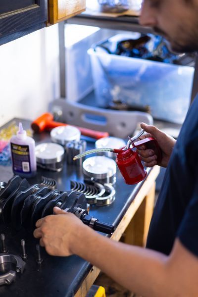 A man is working on a piece of metal with a spray bottle.