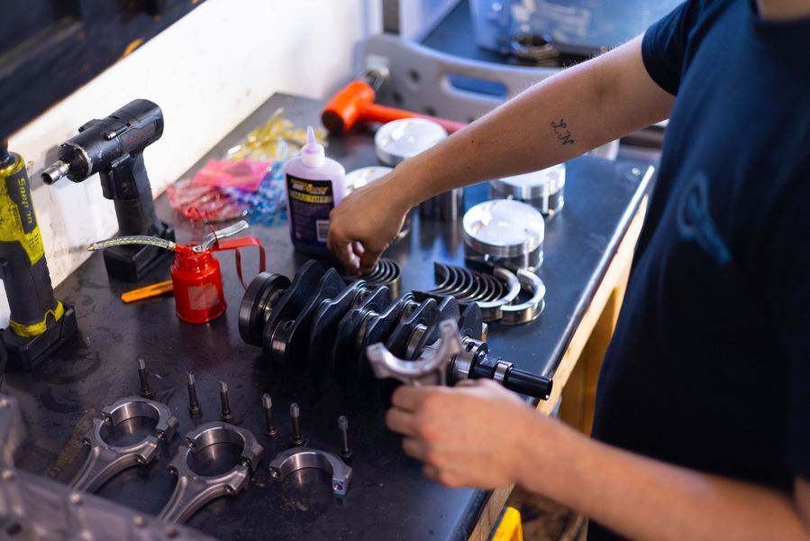 A person is working on a crankshaft in a garage.