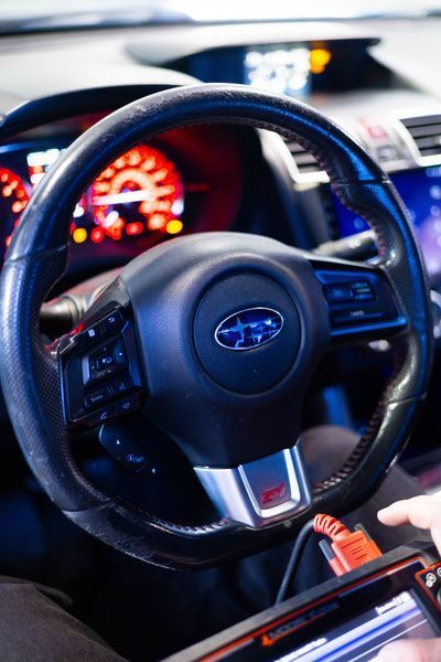 A person is sitting in a subaru car using a tablet.