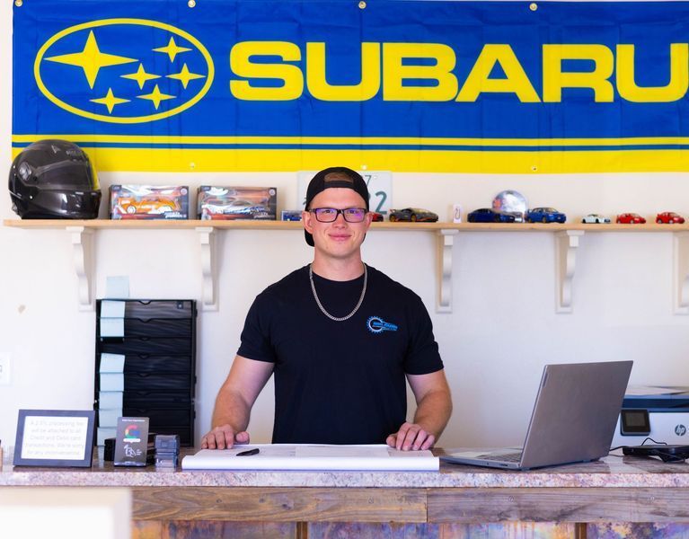 A man is standing in front of a subaru sign