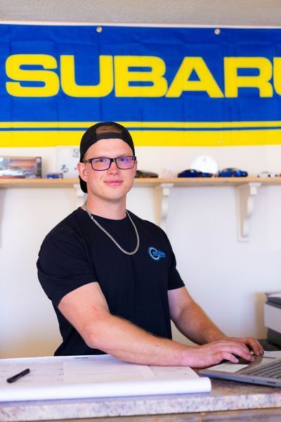 A man sitting in front of a subaru sign