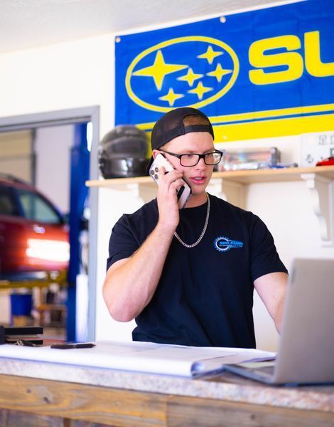 A man talking on a cell phone in front of a subaru banner
