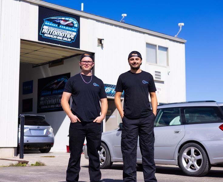 Two men standing in front of a building that says automotive