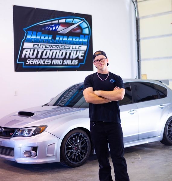 A man stands in front of an automotive services and sales sign