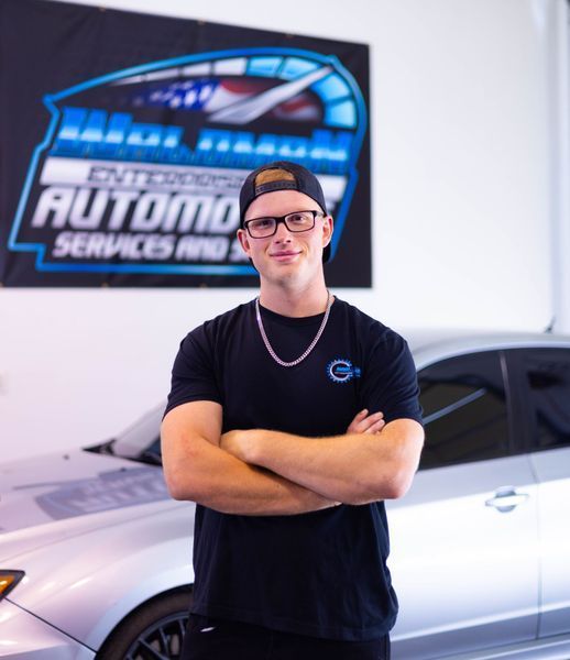 A man standing in front of a car with his arms crossed