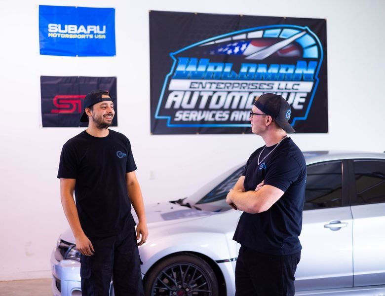 Two men are standing in front of a subaru car