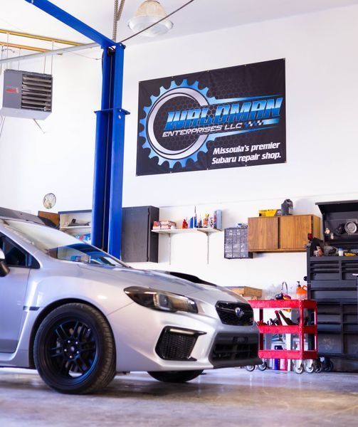 A silver car is parked in a garage with a sign above it that says high velocity