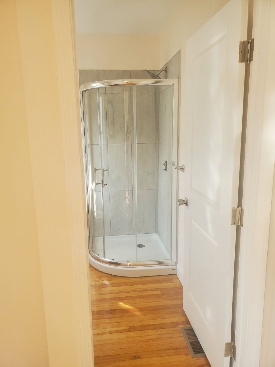 A Bathroom with a walk-in shower and a white door – Malden, MA – EG Remodeling LLC