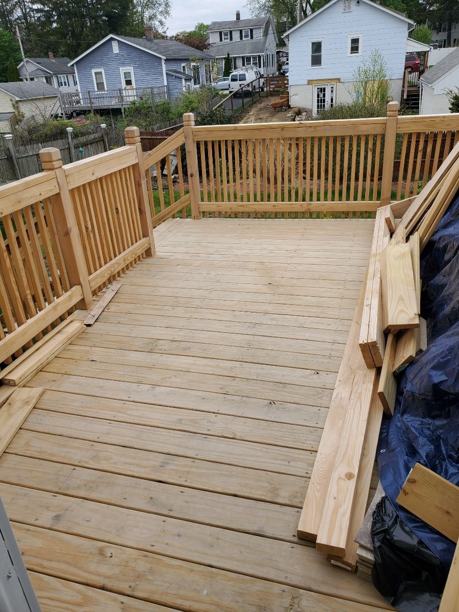 A Wooden Deck with a blue house in the background – Malden, MA – EG Remodeling LLC