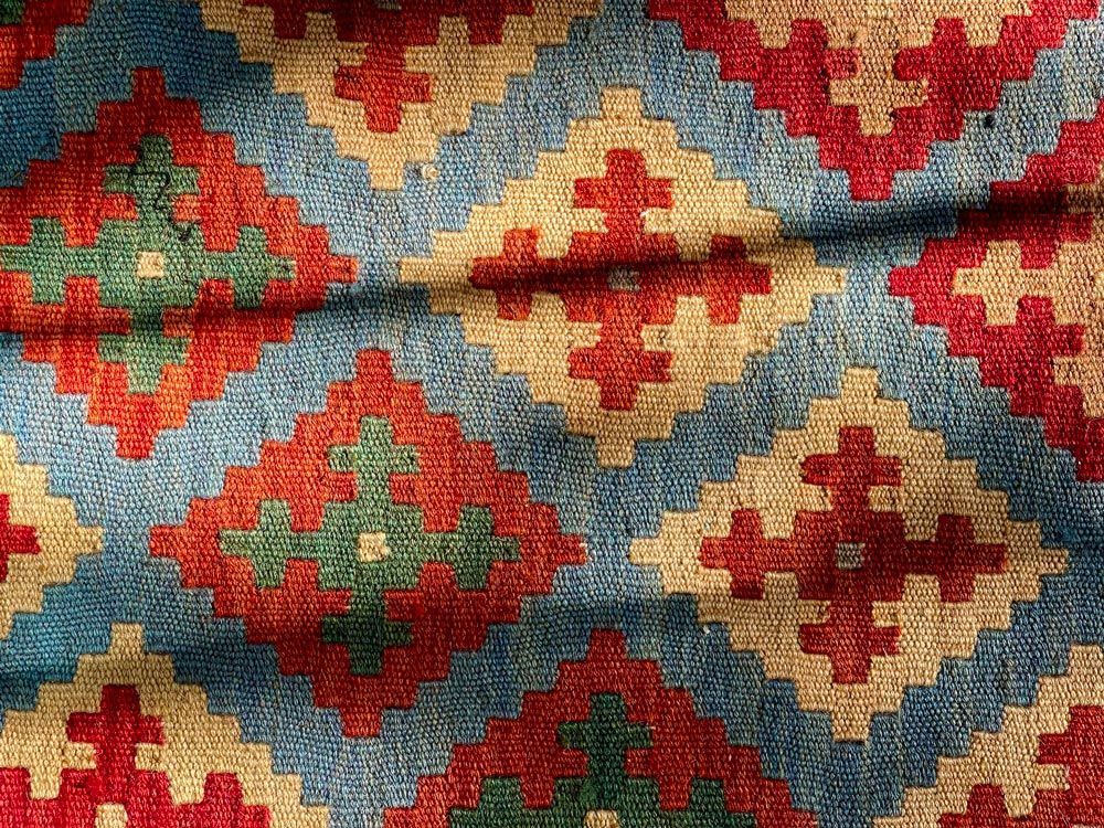 Colorful woven rug with red, blue, green, and beige geometric patterns. Colorful woven rug with red, blue, green, and beige geometric patterns.