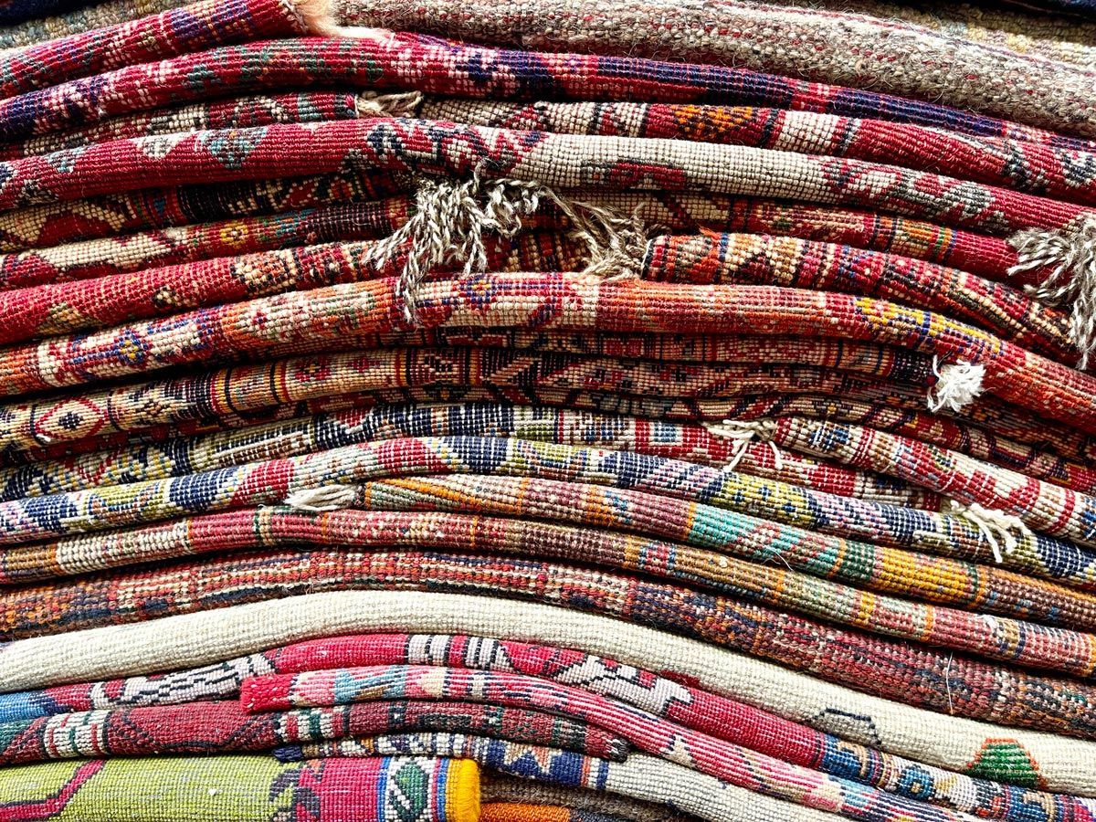 Stack of colorful, intricately patterned Oriental rugs.