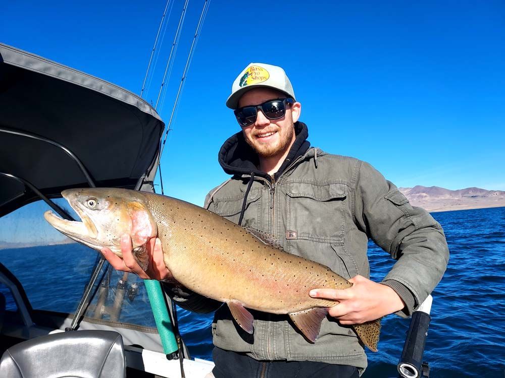 A man on a boat holding a large fish