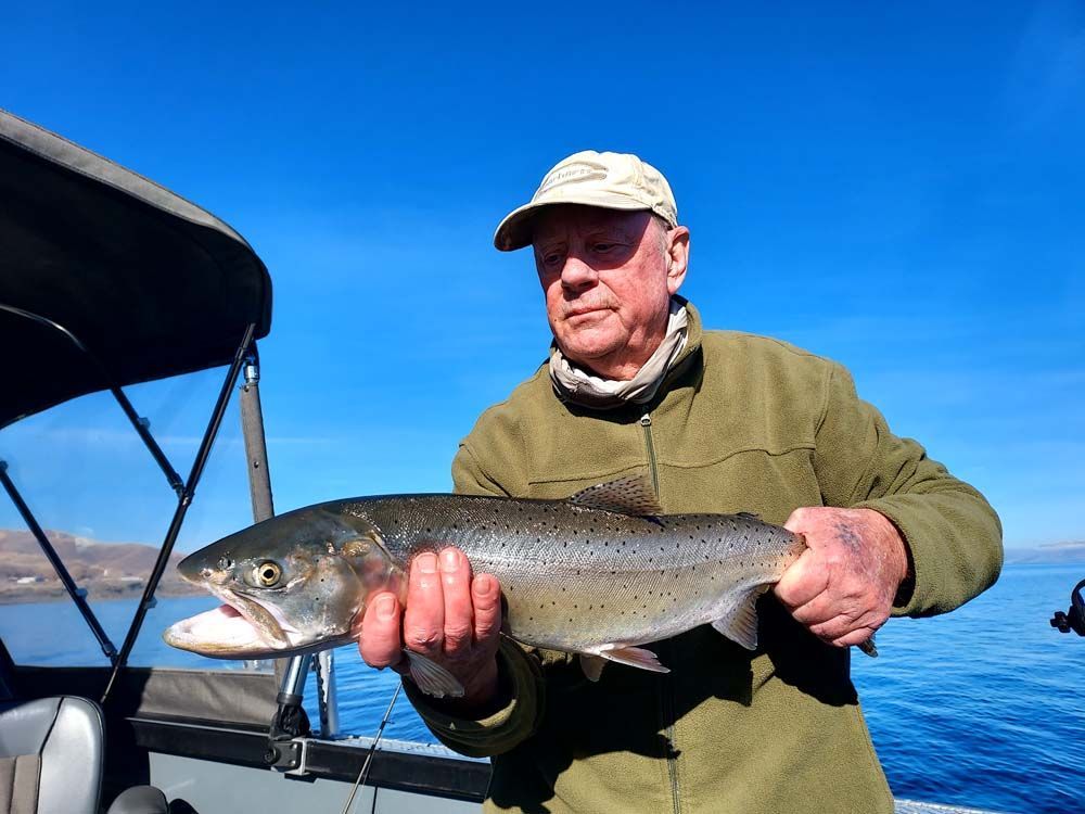 A man is holding a fish in his hands on a boat.