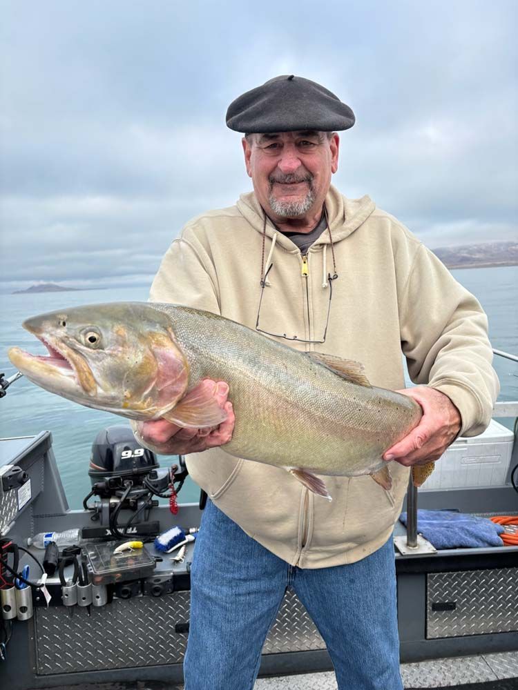 A man is holding a large fish in his hands on a boat.