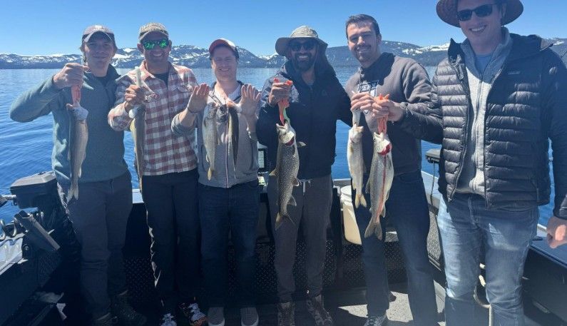 A group of people are standing on a boat holding fish.