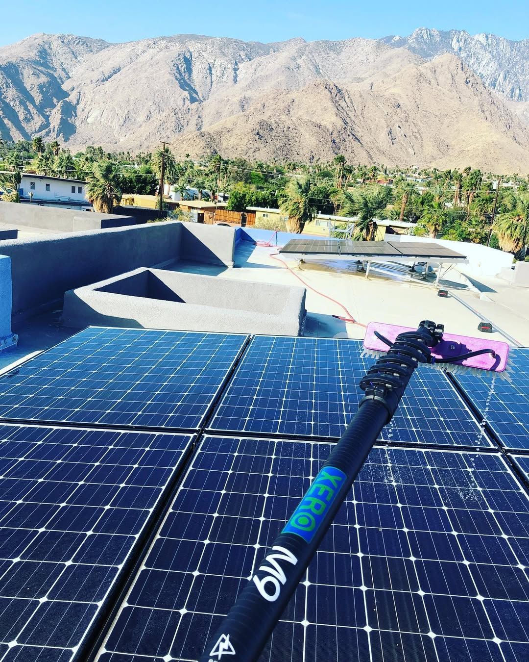 A person is cleaning solar panels on the roof of a building.