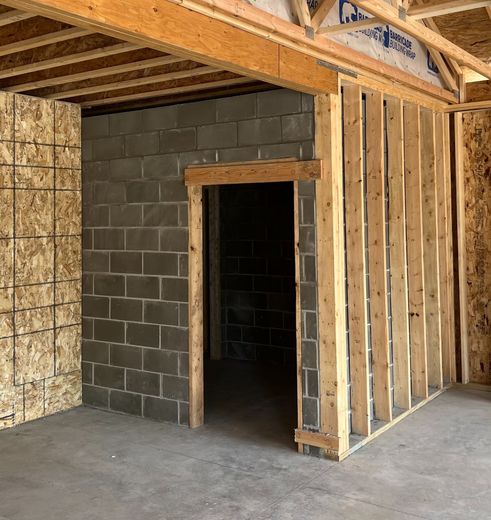 Interior construction: unfinished room with cinder block walls, a doorway, and exposed wood framing.