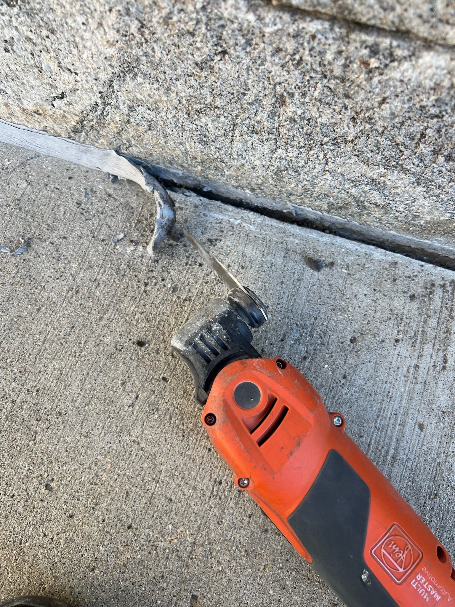 Orange power tool cutting a thin line in concrete.
