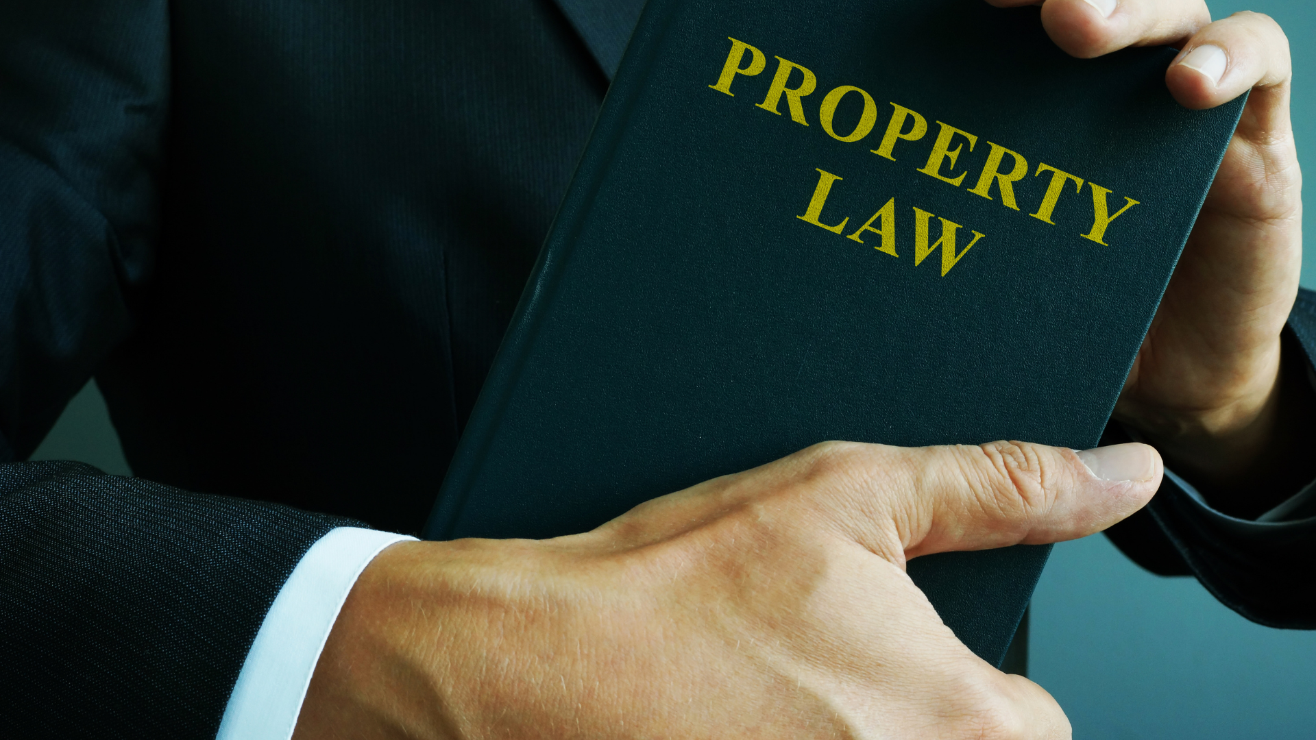 A man in a suit is holding a book titled property law