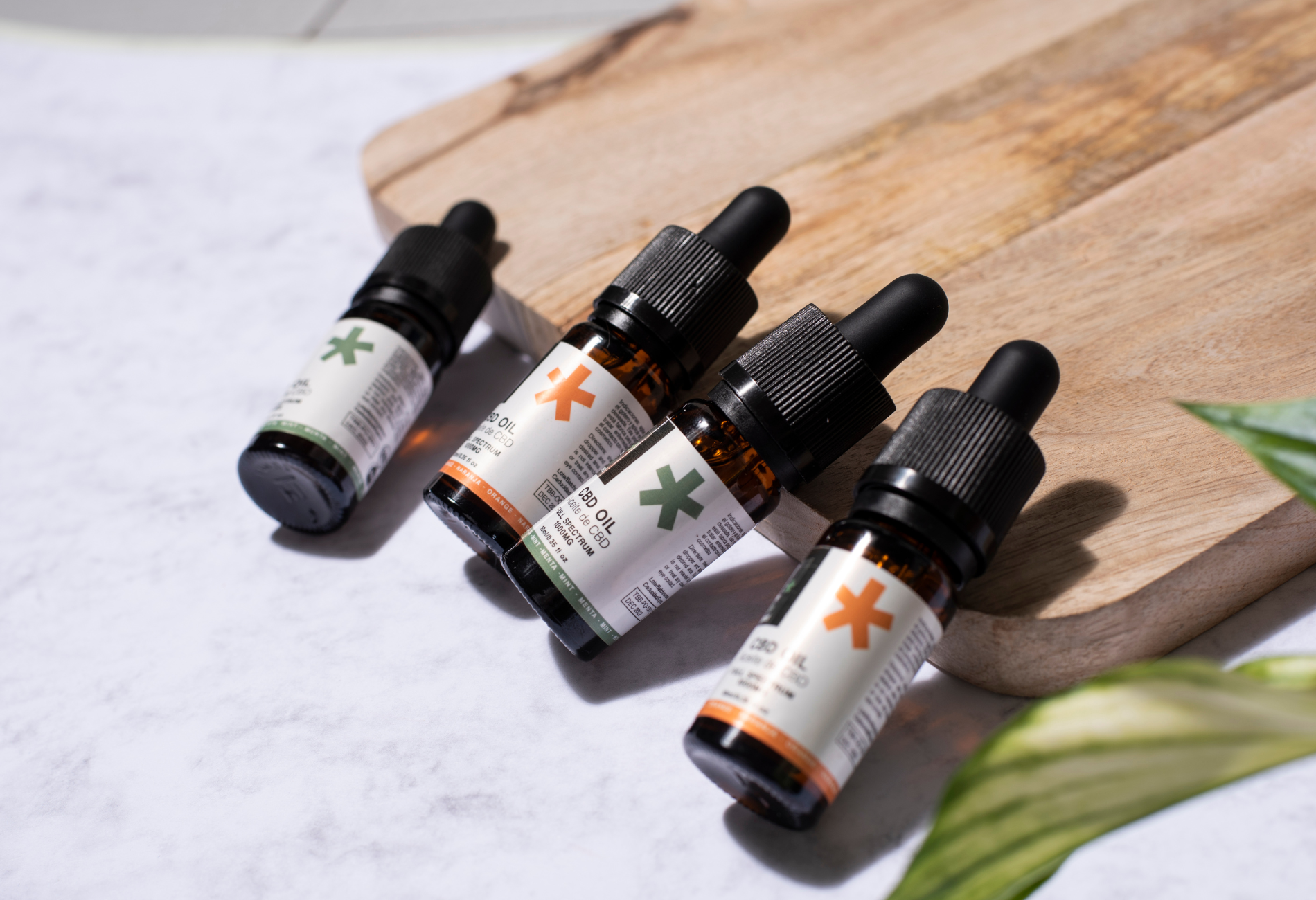 Four bottles of essential oil are sitting on a wooden cutting board.