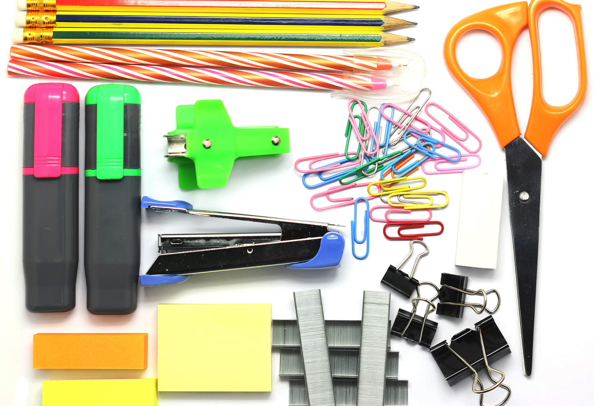 A variety of office supplies are laid out on a white surface