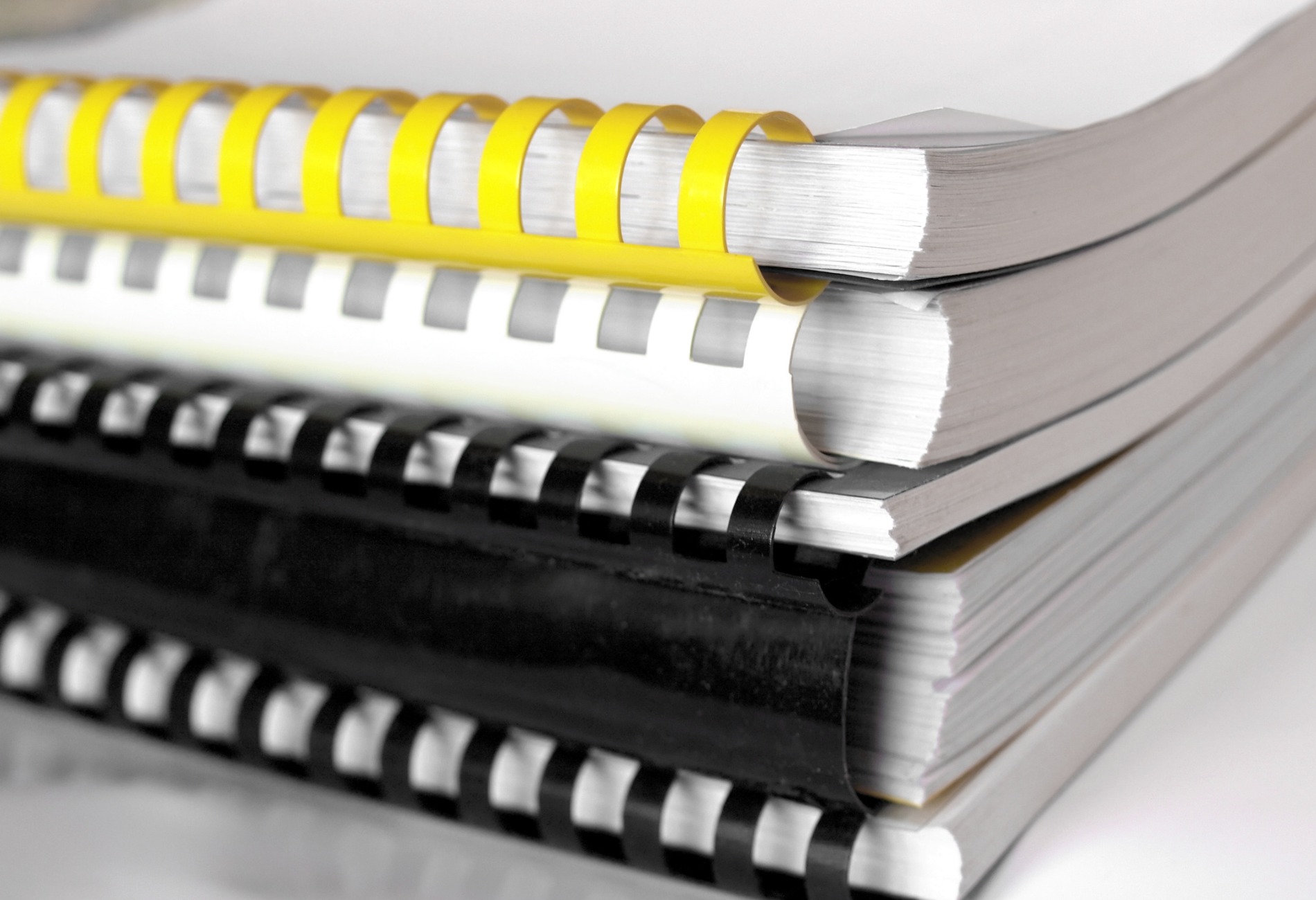 A stack of spiral bound books with yellow and black bindings