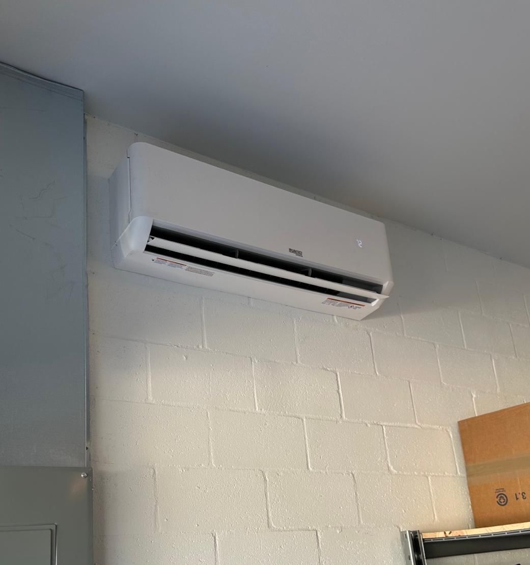 White wall-mounted air conditioner on a white brick wall.