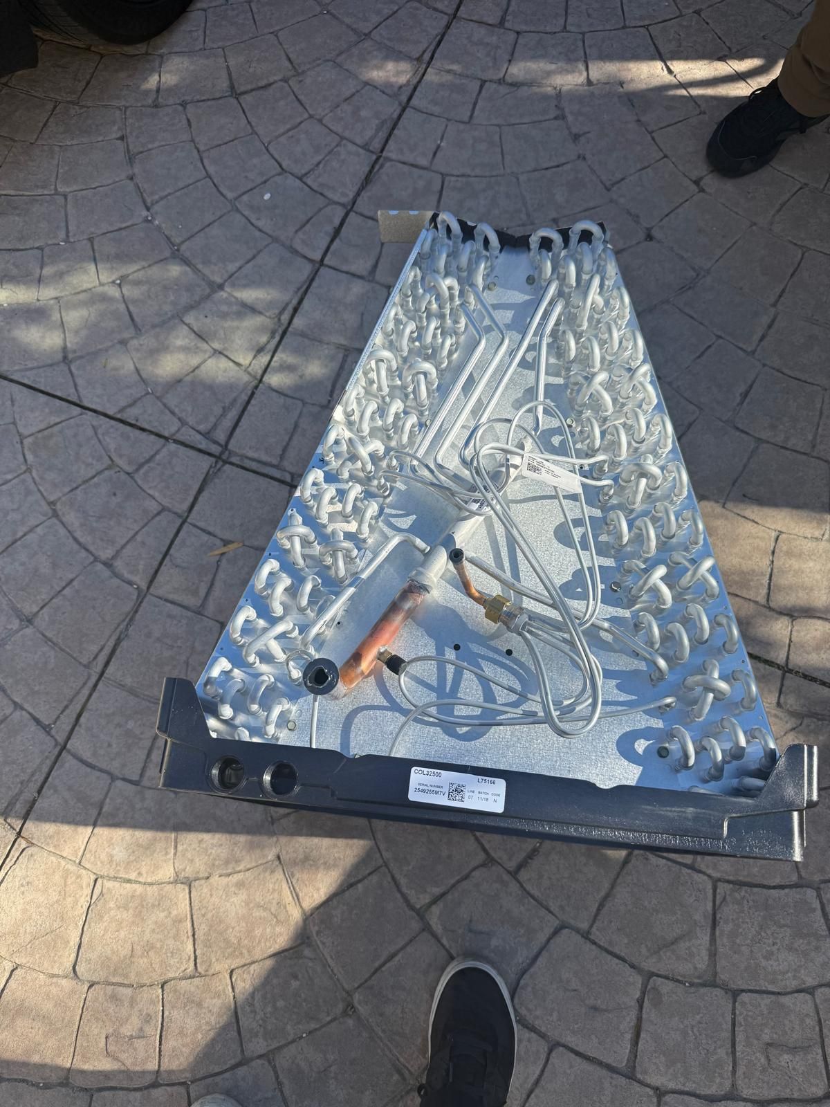 Triangular metal HVAC coil on patterned concrete.