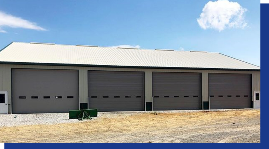 A modern home exterior with a light-colored garage door, a dark front door, stone walls, and a balcony with a black railing.