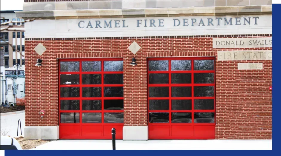 A modern home exterior with a light-colored garage door, a dark front door, stone walls, and a balcony with a black railing.