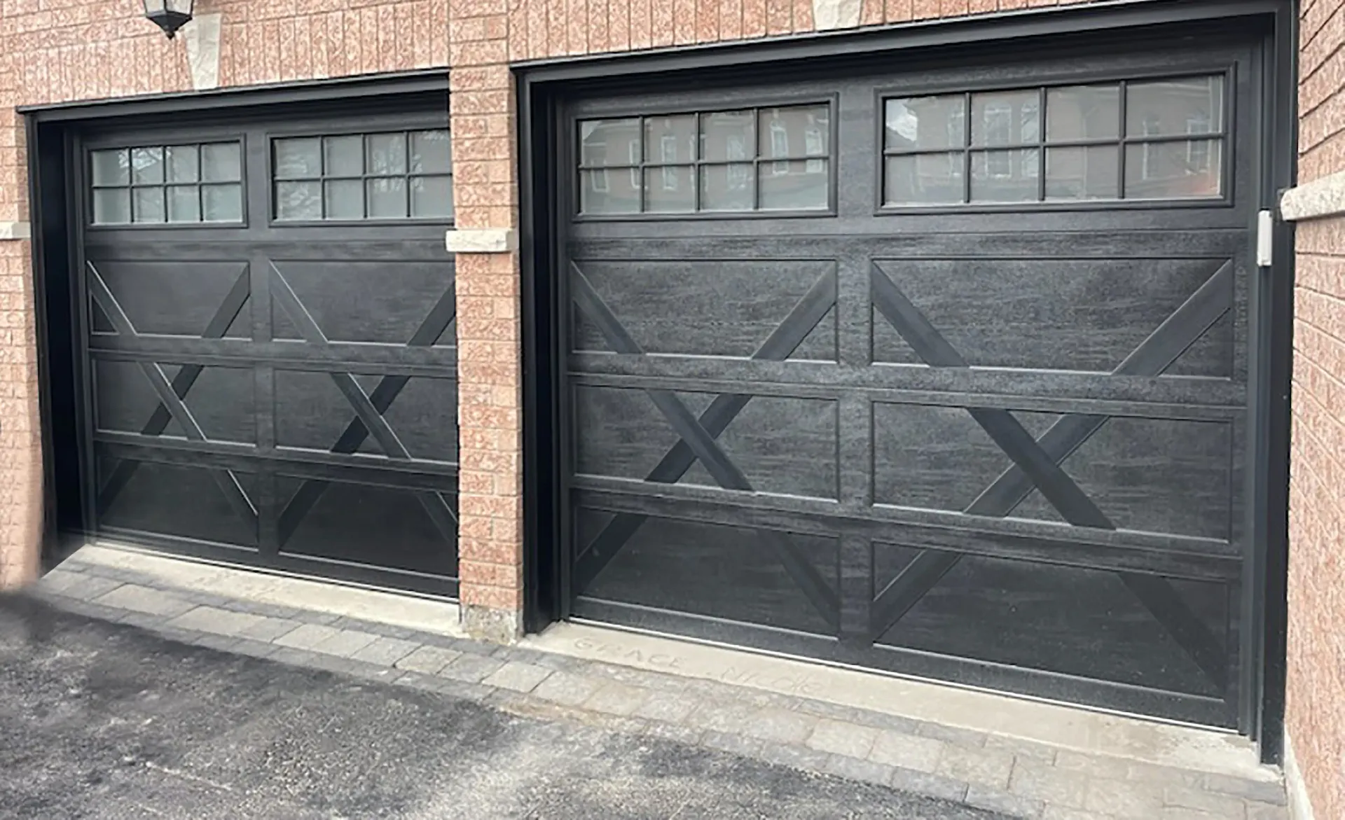 A modern home exterior with a light-colored garage door, a dark front door, stone walls, and a balcony with a black railing.