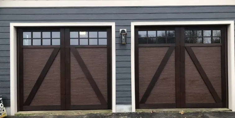 A modern home exterior with a light-colored garage door, a dark front door, stone walls, and a balcony with a black railing.
