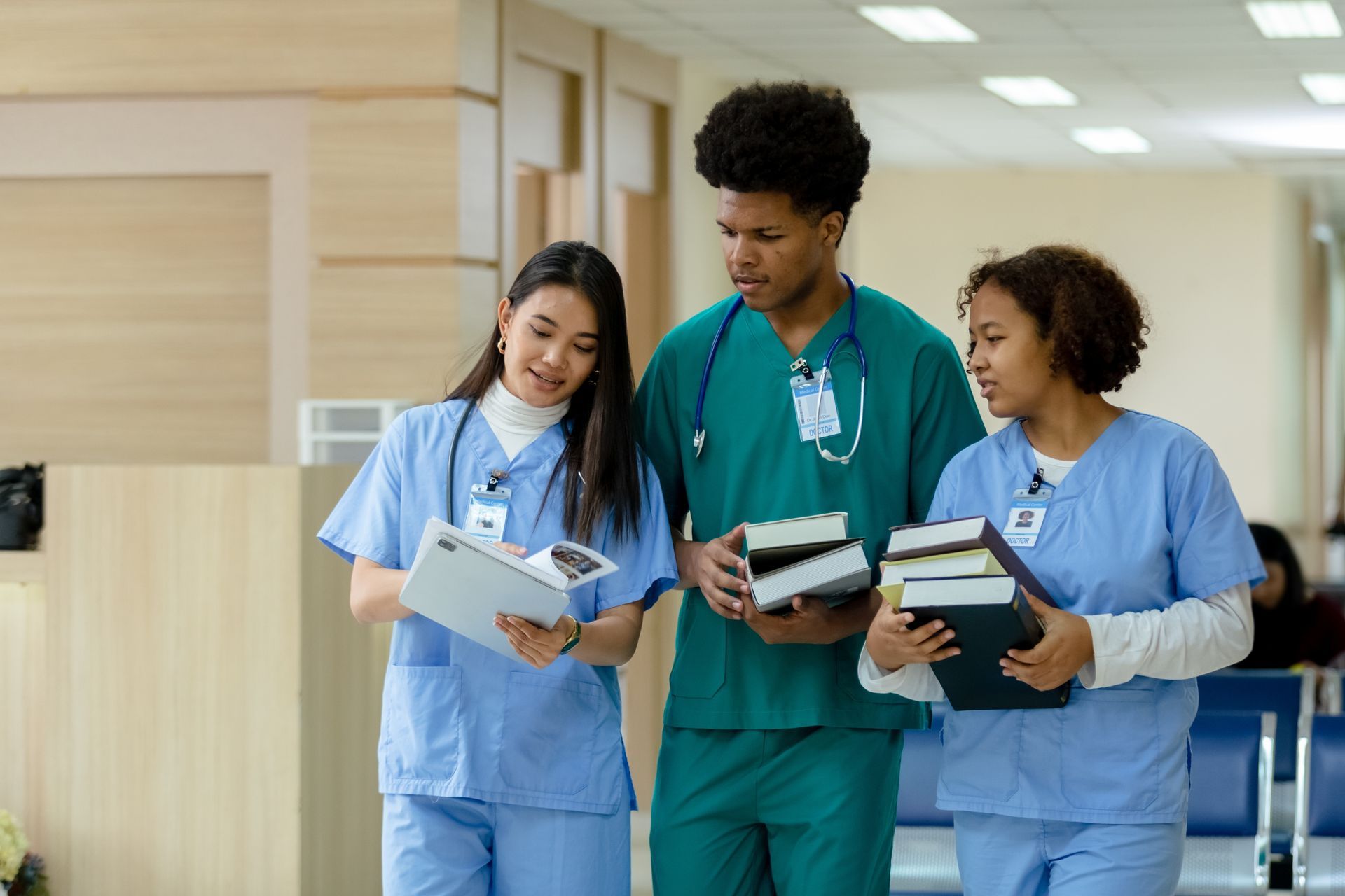 A group of nurses and doctors are walking down a hallway holding books.