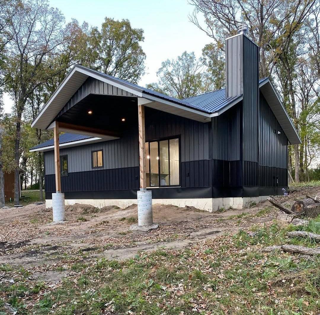 A small house is sitting on top of a dirt hill in the middle of a forest.