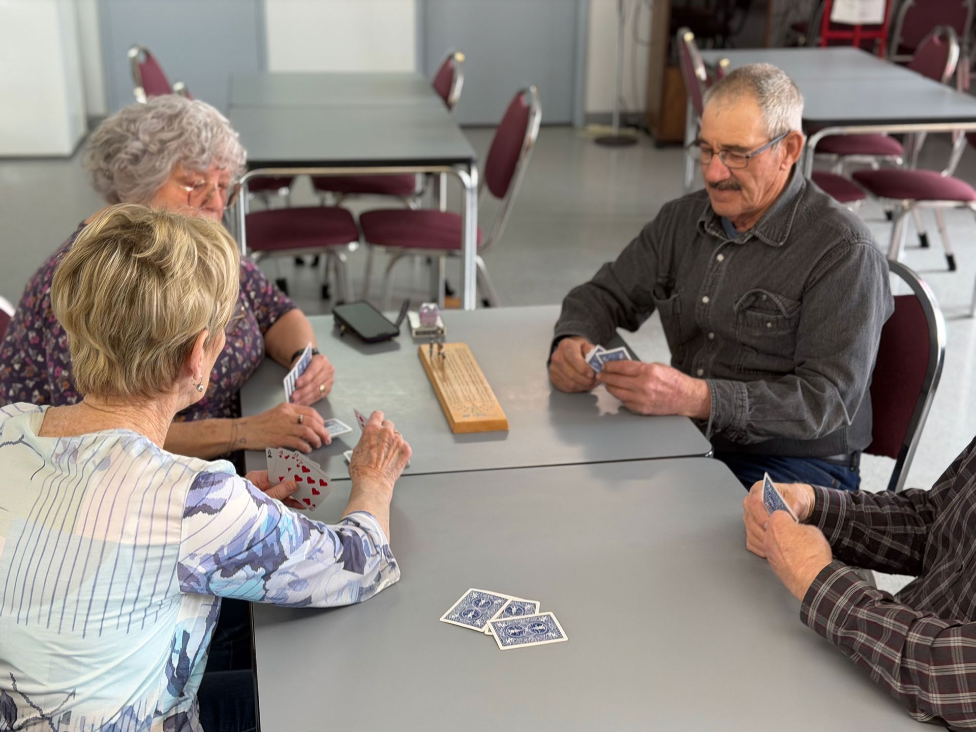A single-story, tan-colored museum building in Girouxville with a blue-and-white striped awning and wagon-wheel fence.