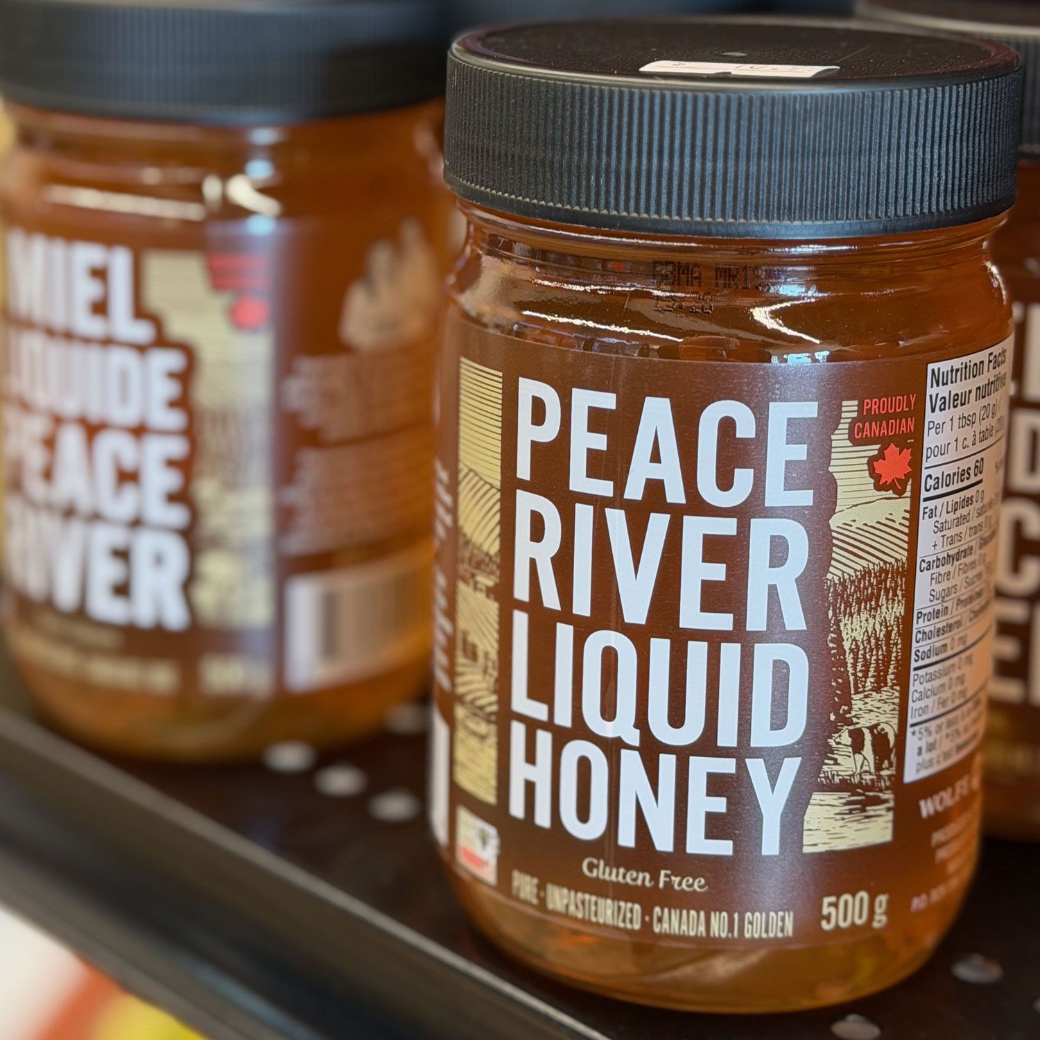 A beekeeper in a protective suit points at a bee-covered frame while inspecting a hive outdoors.