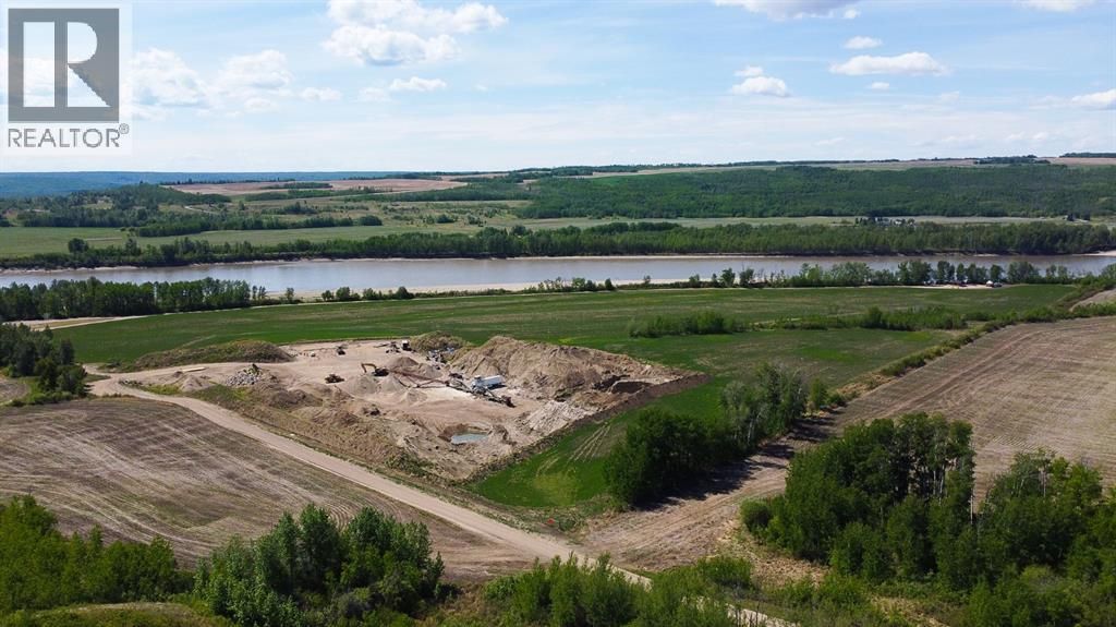 Three green John Deere combine harvesters move through a dry, harvested field under a clear blue sky.