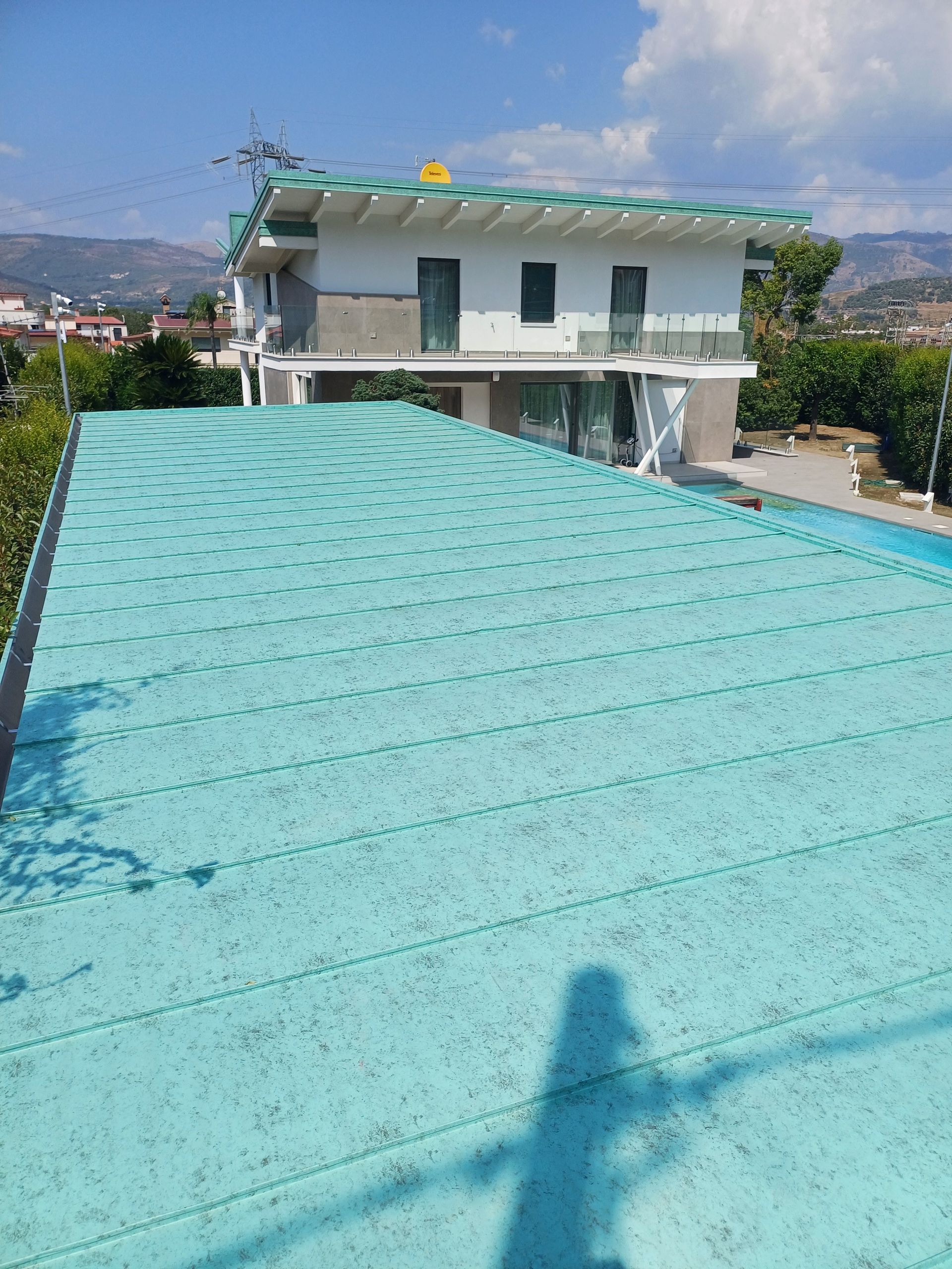 Una casa con un tetto verde e l'ombra di una persona su di esso
