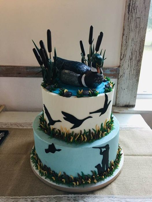 Three-tier cake with black fish silhouettes and seaweed decorations on a white and blue ocean-themed base